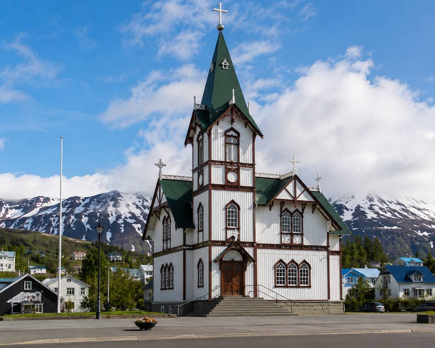 Husavikurkirkja Church in Iceland under a blue, cloudy sky.