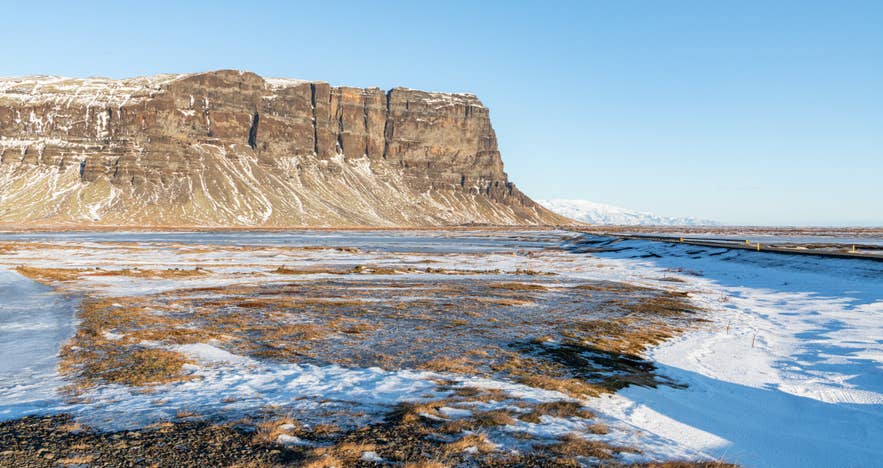 Schneebedeckte Ebene mit dem Berg Lómagnúpur im Süden Islands.