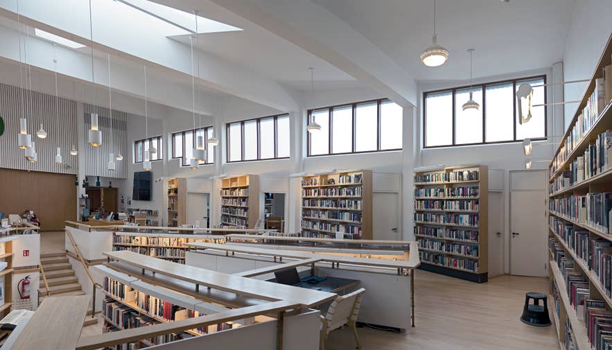 Interior of the Nordic House library in Reykjavík with bright windows, bookshelves, modern lights, and study areas.