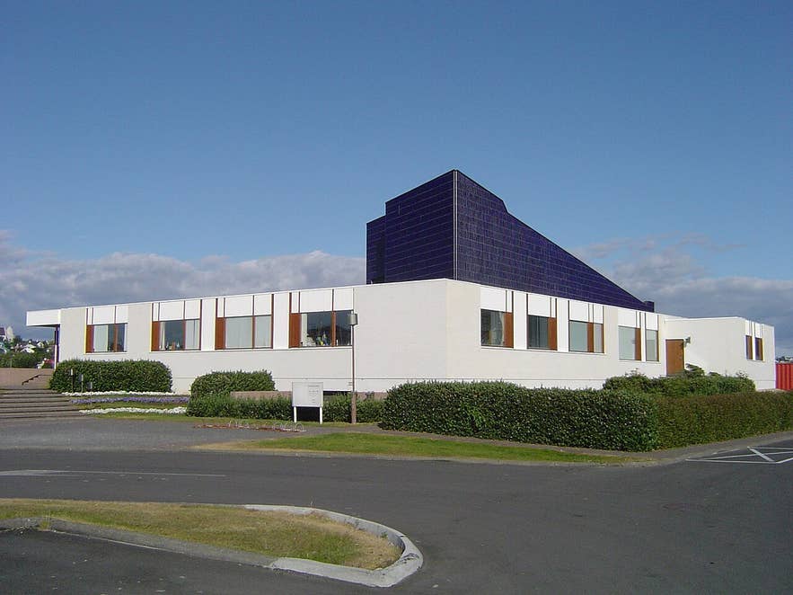 Nordic House in Reykjavík, Iceland, with white facade, brown‑framed windows, and bold dark blue pyramid roof.
