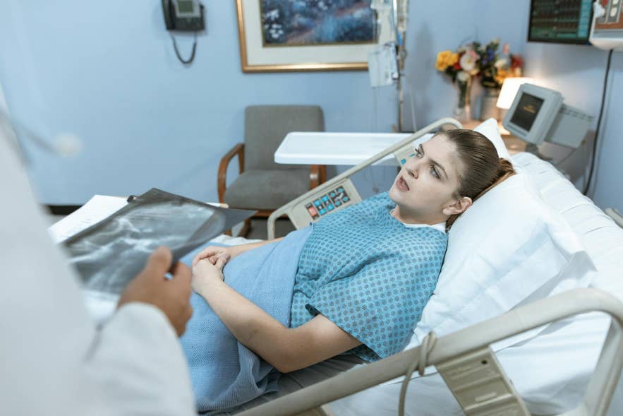Eine Patientin im Bett spricht mit einem Arzt im Krankenhauszimmer