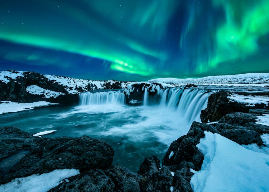 Green northern lights dancing above Godafoss Waterfall.