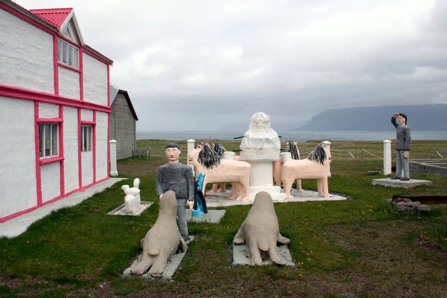 Samuel Jónsson Art Farm in Selárdalur Valley, Iceland, with sculptures and buildings framed by grassy hills.