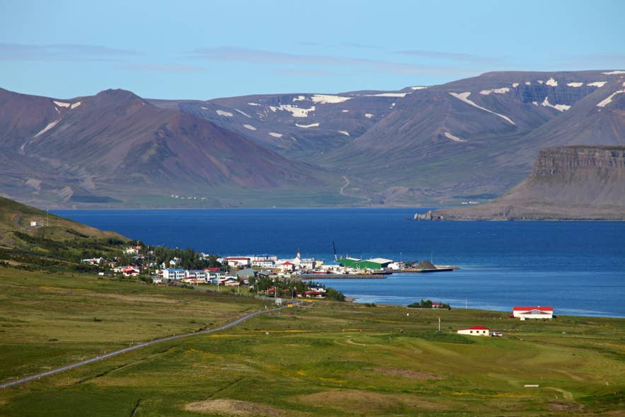 Bildudalur fishing village on Arnarfjörður, Westfjords, Iceland, with harbor, fjord, and snow‑capped mountains.