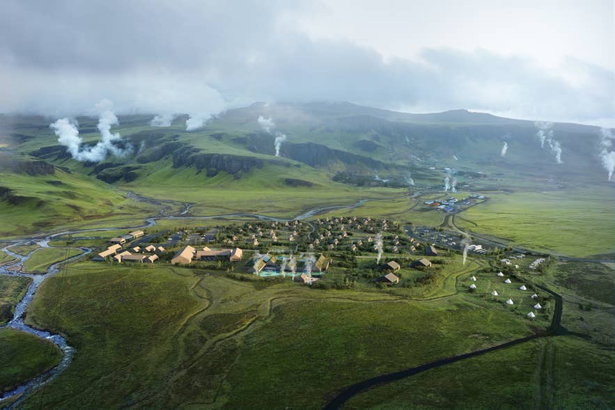 A panoramic view of Reykjadalur Valley in South Iceland, with mountains in the background and steams rising from the ground.
