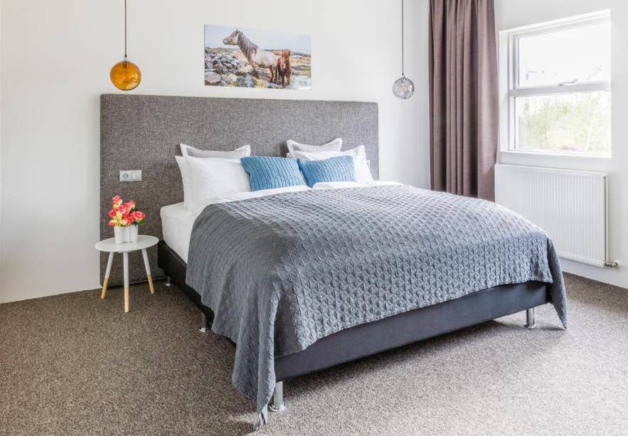 A modern Litli Geysir Hotel room with a double bed and horse artwork near the Geysir Geothermal Area.