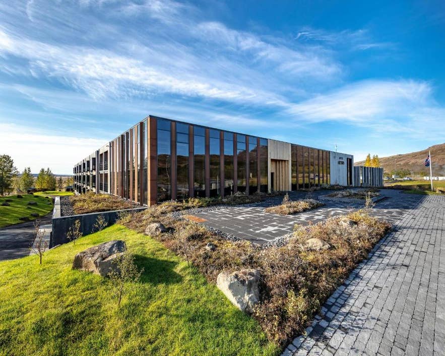 The timber-clad Hotel Geysir building stands beside green lawns across from the Geysir Geothermal Area.