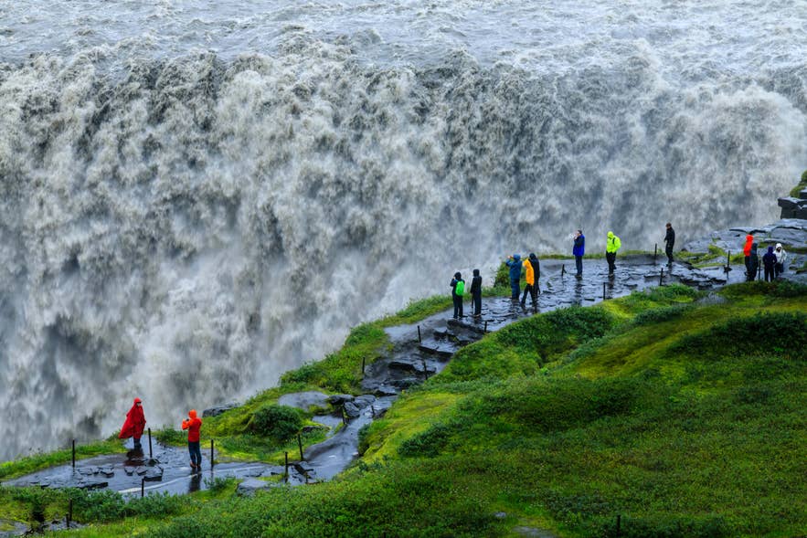 De waterval Dettifoss in de zomer, met een begeleide groep bij het rotsachtige uitzichtpunt.
