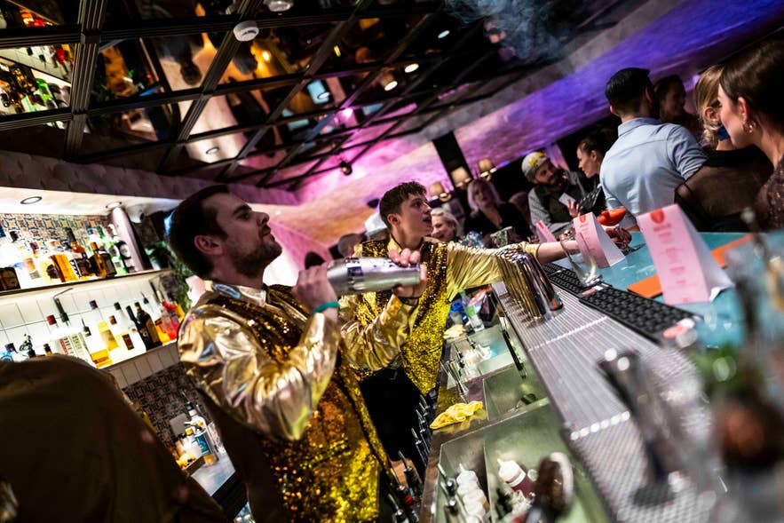 Barman in een gouden jasje met pailletten die cocktails bereidt bij Pablo Discobar in het centrum van Reykjavik.