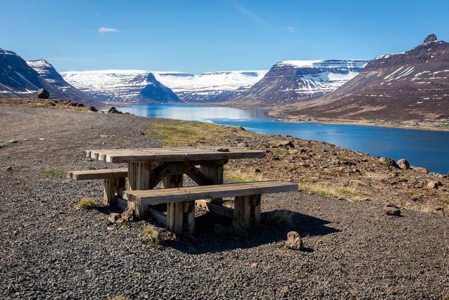 Summer landscape of mountains and calm fjords in the Westfjords under clear skies.