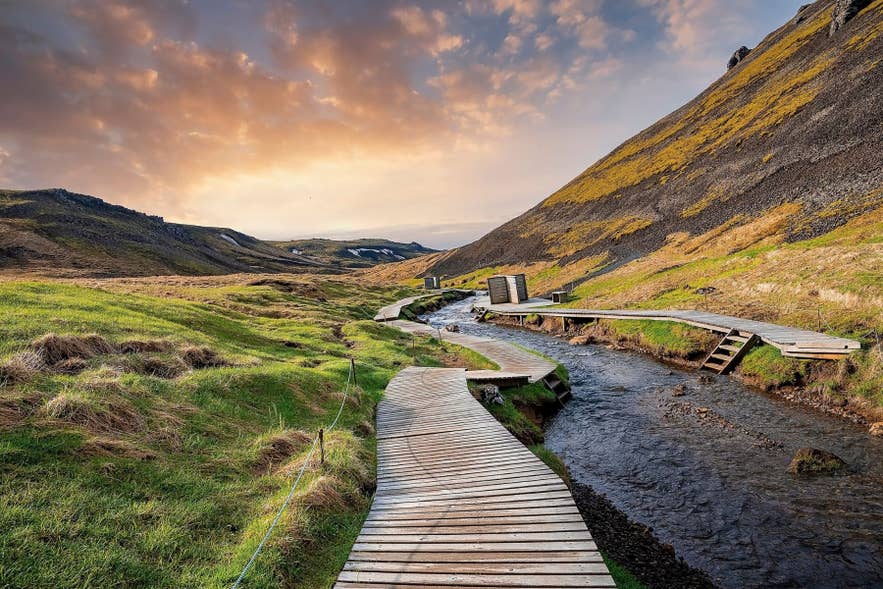 Wooden boardwalk and path winding through the steaming Reykjadalur Hot Spring Valley
