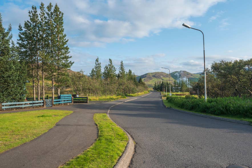 Straße in Hveragerdi mit geothermischen Hügeln im Hintergrund. Dies ist der letzte Servicepunkt vor dem Reykjadalur-Wanderweg. Straße in Hveragerdi mit geothermischen Hügeln im Hintergrund. Dies ist der letzte Servicepunkt vor dem Reykjadalur-Wanderweg.
