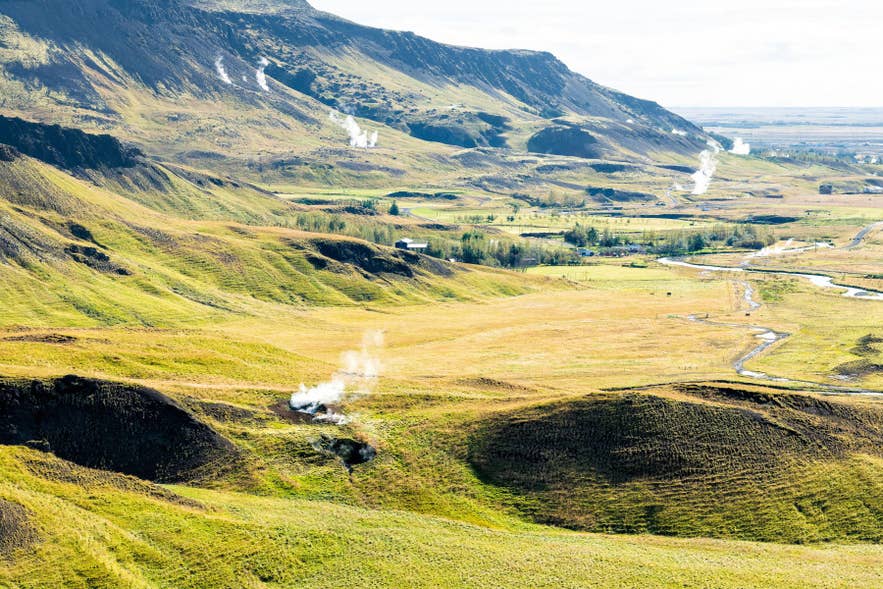 Dampf steigt aus dem bunten geothermischen Boden des Reykjadalur-Tals in Südisland entlang eines Pfades auf. Dampf steigt aus dem bunten geothermischen Boden des Reykjadalur-Tals in Südisland entlang eines Pfades auf.