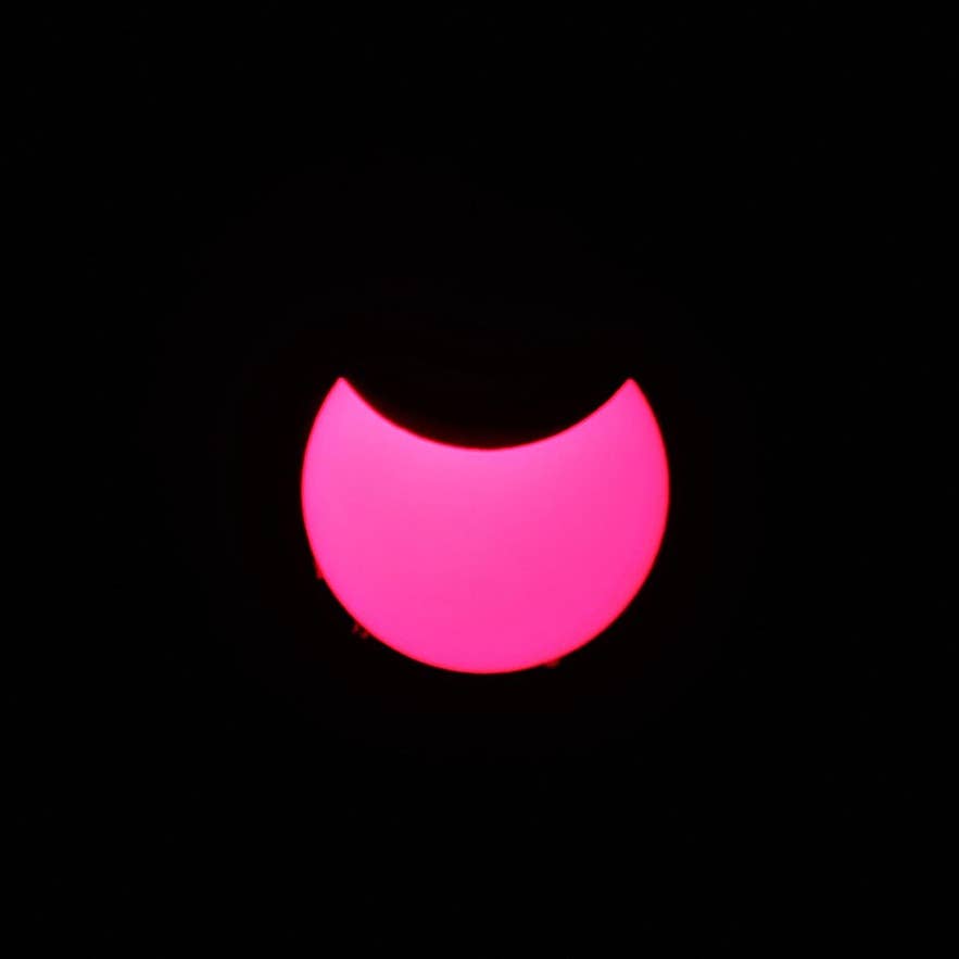 A partial solar eclipse photographed through a solar telescope, showing the sun reduced to a bright crescent
