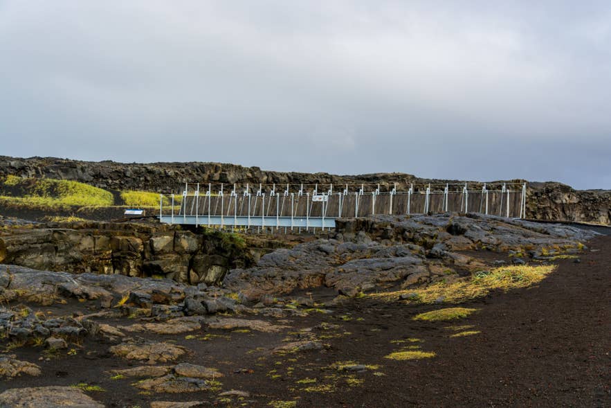 Bridge Between Continents spans volcanic rift at Sandvík, linking Eurasian and North American plates.