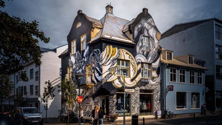 A historic building covered in black-and-white street art stands along Laugavegur in downtown Reykjavik, blending architecture and urban creativity.