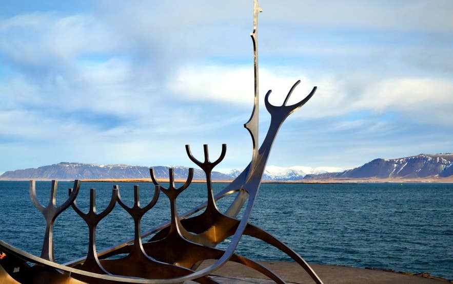 The Sun Voyager sculpture stands along Reykjavik’s waterfront, with Faxafloi Bay and snow-capped mountains in the background.