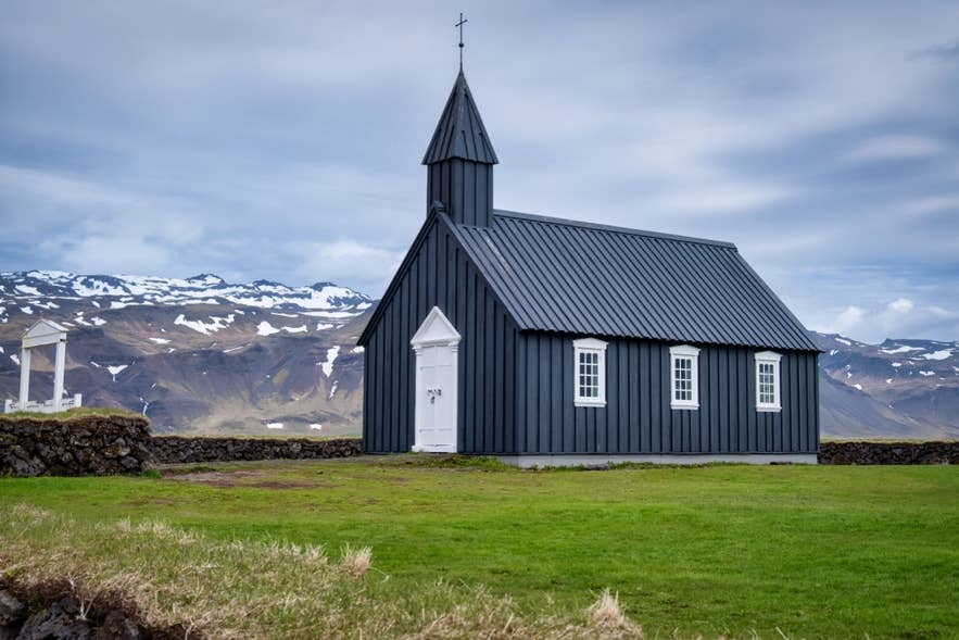Black Church of Budir on a sunny day, standing against a bright sky in the Icelandic countryside.
