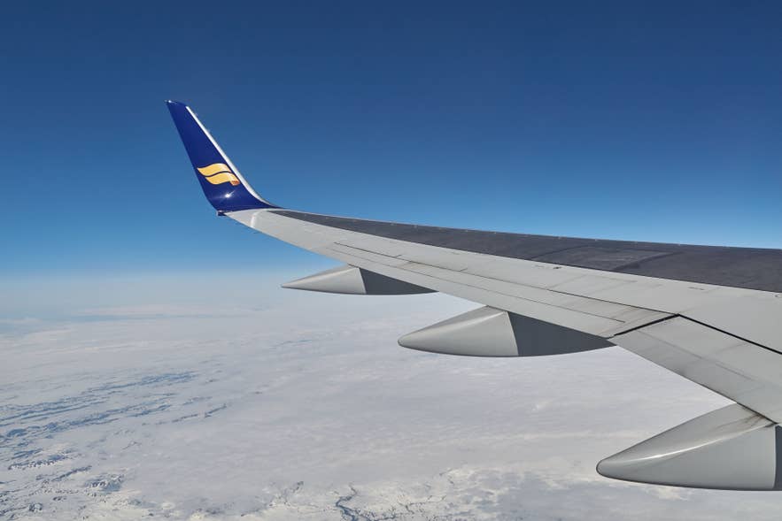 Aile d’un avion Icelandair au-dessus des paysages enneigés de l’Islande par temps clair.