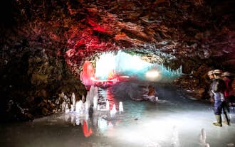 A visitor explores the glowing interior of Lofthellir Ice Cave on a super jeep tour from Akureyri.