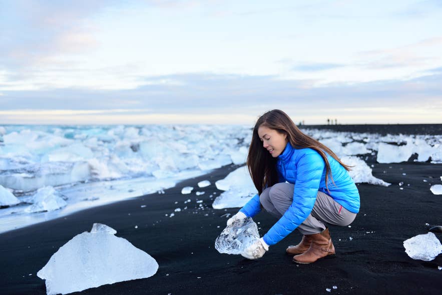 Glanzende ijsbrokken verspreid over het zwarte zand van Diamond Beach naast de Jokulsarlon-gletsjerlagune.