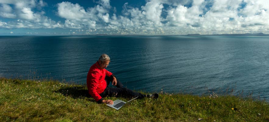 A person working on a laptop while watching the ocean in Iceland. A person working on a laptop while watching the ocean in Iceland.