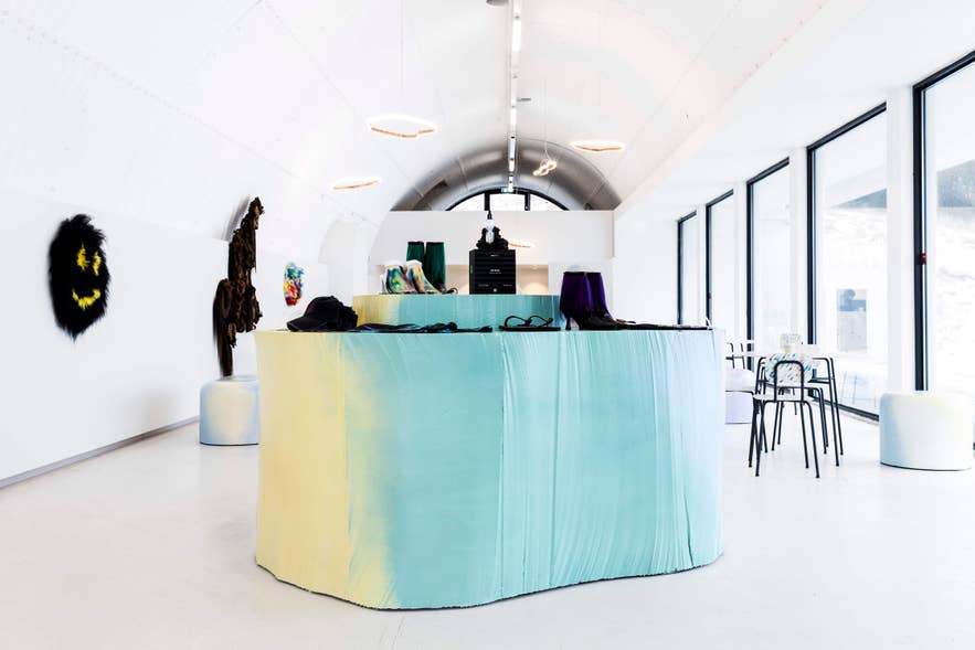 Hofudstodin's lounge and souvenir-making space with pastel display tables and tall glass windows.