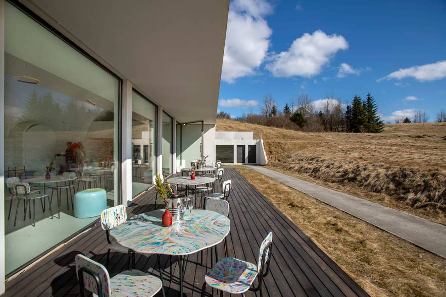 Hofudstodin's wooden outdoor patio set with tables and wine glasses, looking out over the surrounding green valley.