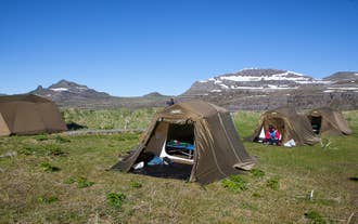 Tents pitched at a wilderness campsite below the mountains in Hornstrandir Nature Reserve.