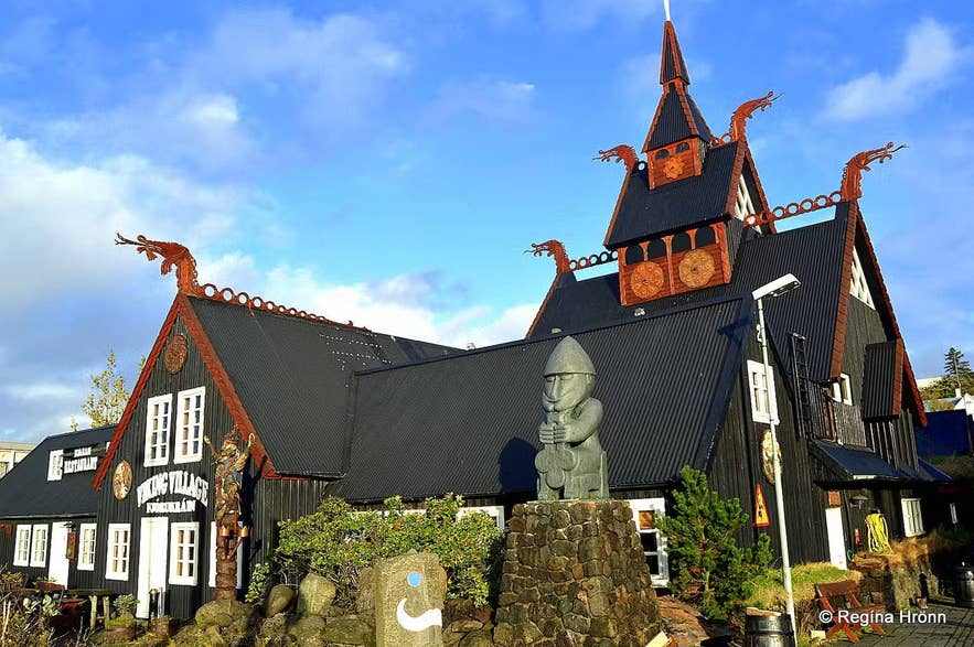 Dark timber Viking Village building with carved dragon-head gables and a Viking statue