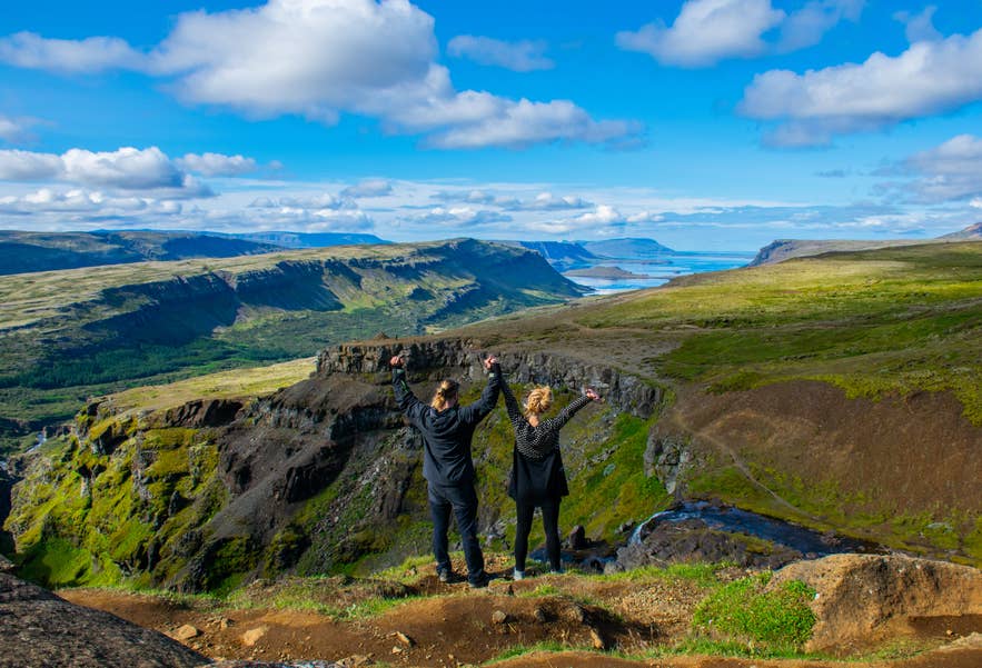 Two hikers on the canyon rim above Glymur Waterfall at the head of Hvalfjordur.