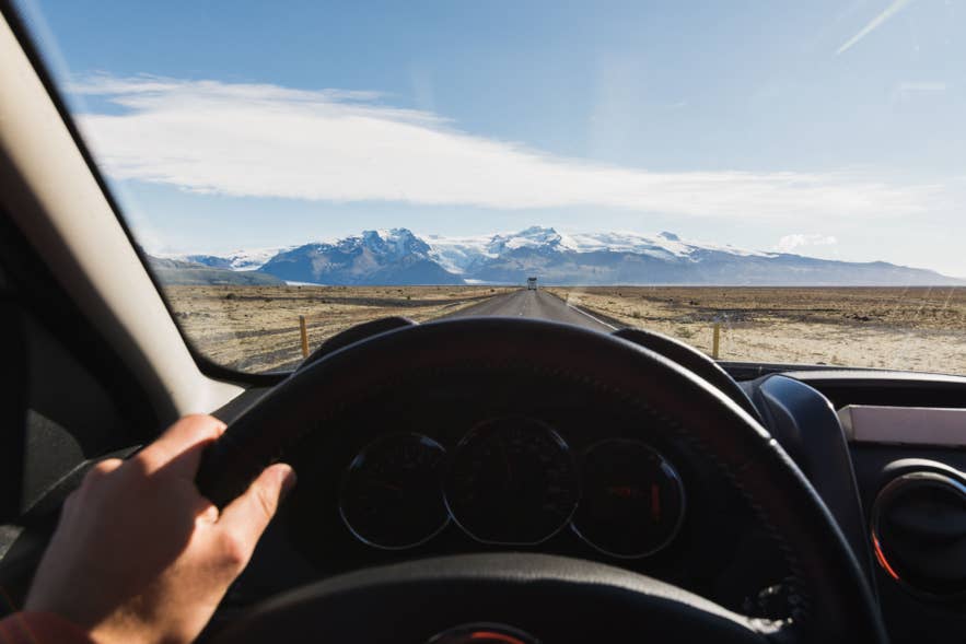 Driver holding the steering wheel while driving through North Iceland.