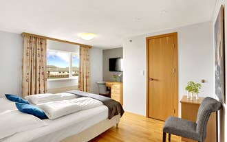 Double room with a wall-mounted TV and a bright window at Airport Eldey Hotel in Keflavik.