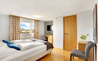 Double room with a wall-mounted TV and a bright window at Airport Eldey Hotel in Keflavik.