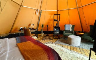 Interior of a heated Nordic tipi with a large bed and wool bedding at Sorla Camp near Hella.