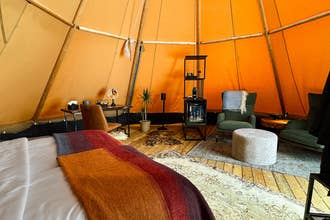 Interior of a heated Nordic tipi with a large bed and wool bedding at Sorla Camp near Hella.