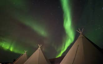 Northern lights glow green over a Nordic tipi at Sorla Camp glamping in South Iceland.