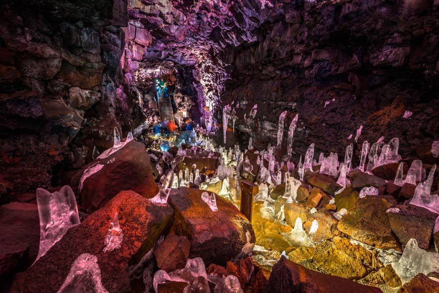 Colorful lights illuminate ice formations inside the Raufarholshellir lava tunnel in South Iceland.