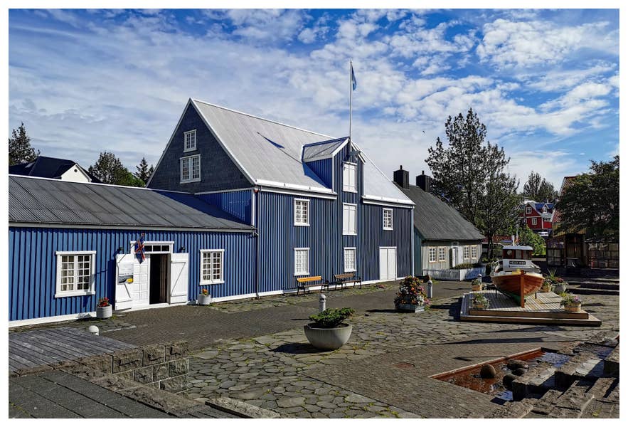 Exterior of Hafnarfjordur Museum with a traditional blue building and historic fishing boat.