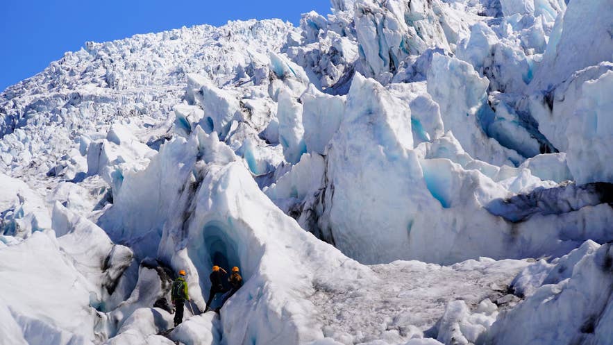Hikers weaving between towering blue seracs on a Falljokull glacier hike.