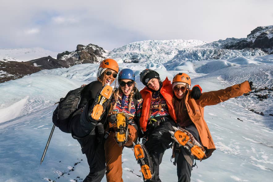 Smiling glacier hikers showing their crampons after a guided tour on Falljokull