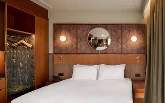 Guest room with a dark wood headboard and round mirror at Skald Hotel Akureyri Curio Collection by Hilton.