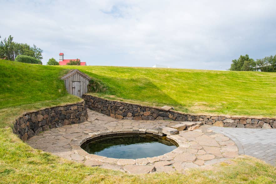 Snorralaug geothermal pool in Reykholt, with the reconstructed tunnel entrance behind it.