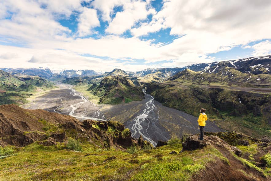 En vandrer med udsigt over de mosklædte kløfter og stejle bjergtoppe med panoramaudsigt i Thorsmörk-dalen.