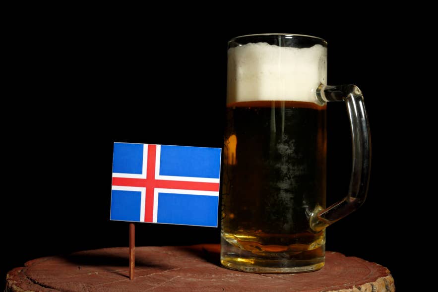 Glass of golden beer with Icelandic flag in the foreground.