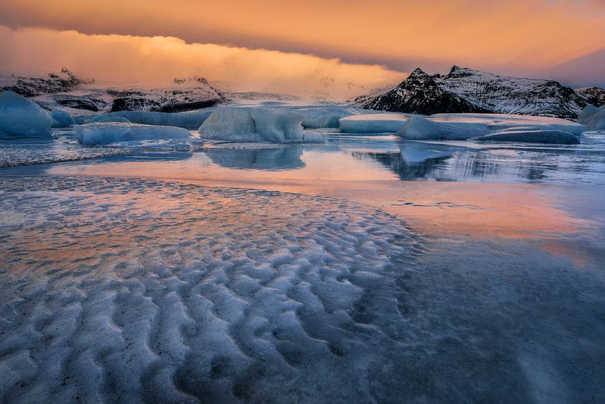Icebergs floating in Jokulsarlon Glacier Lagoon beneath Breidamerkurjokull at sunset