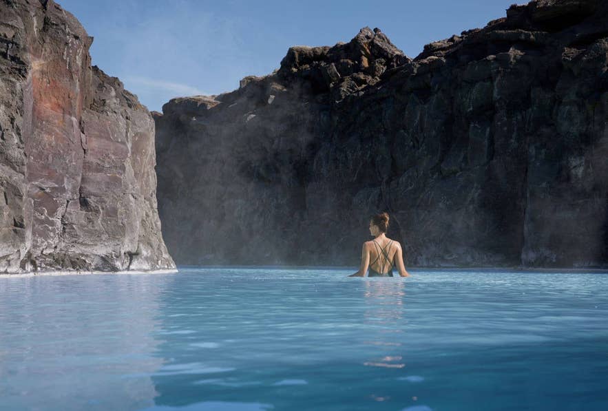 View of the Blue Lagoon's milky-blue water winding through a black lava field in Iceland.