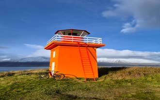 A mountain bike beside Hrisey Lighthouse standing along the island's coastline overlooking the waters of Eyjafjordur.