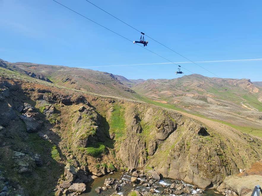 Riders soar over Svartagljufur Canyon on the Mega Zipline in Hveragerdi, the closest thrill to bungee jumping in Iceland.