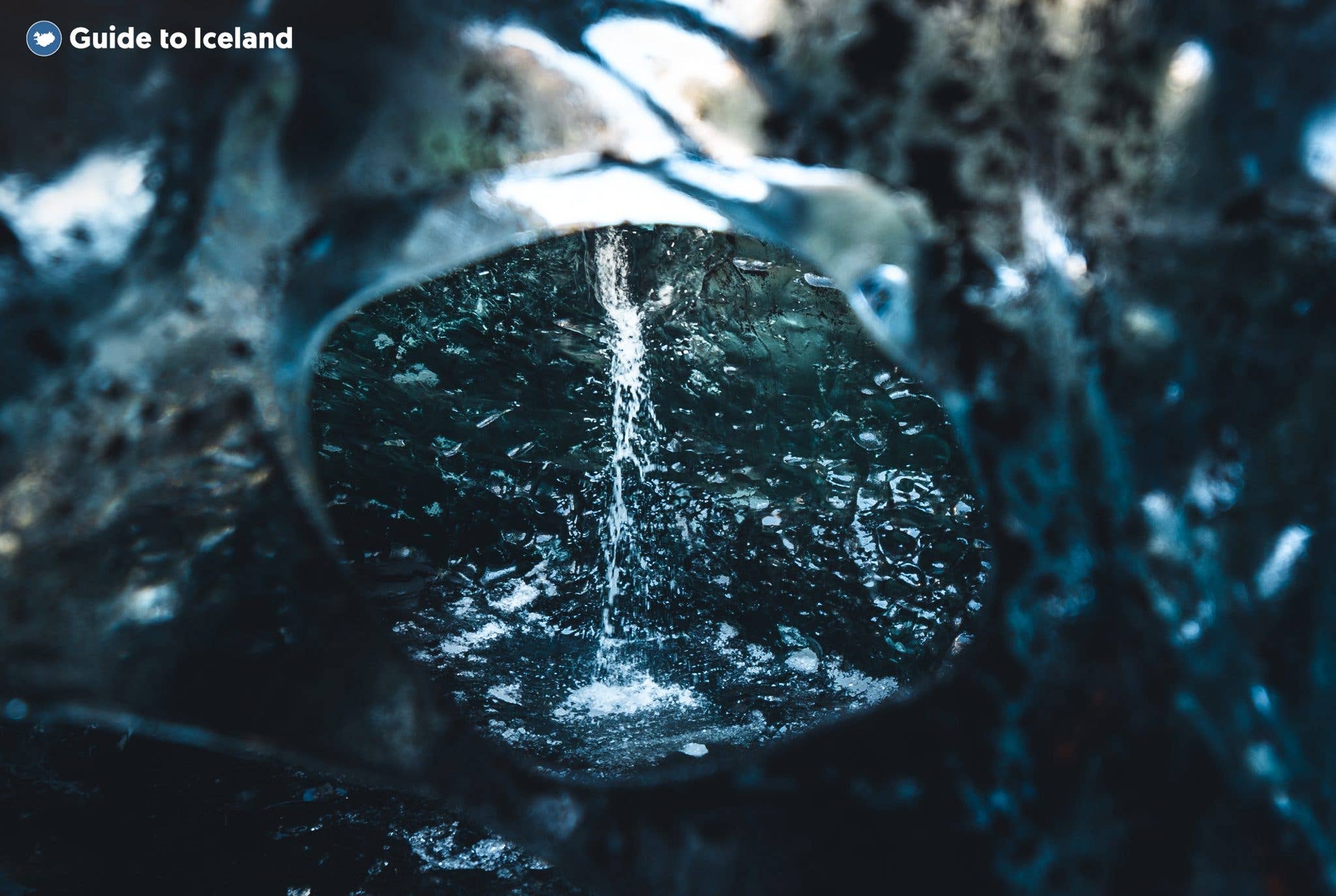 Meltwater trickles over a dark dome of glacier ice inside an ice cave in Vatnajökull, Iceland.
